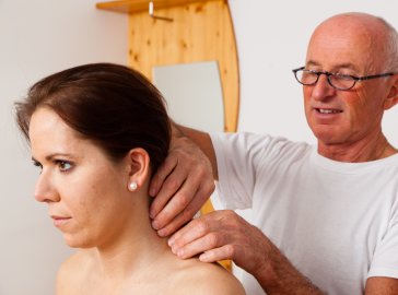 Arzt untersucht Nacken einer Patientin