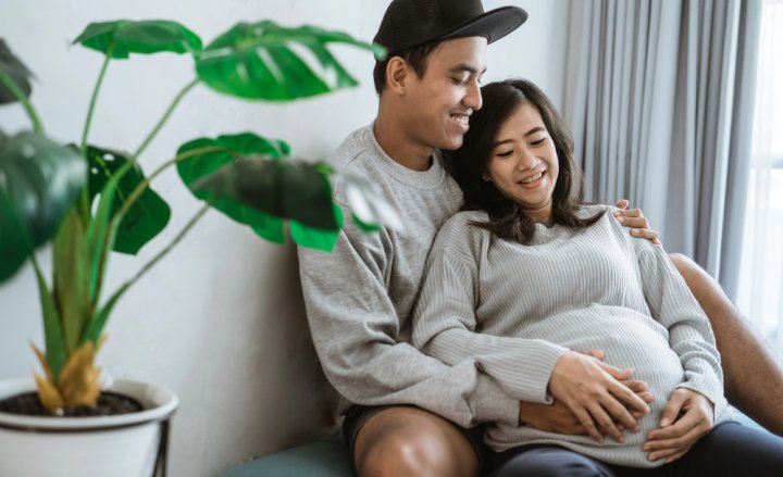 Foto einer Schwangeren und ihres Partners, der sie umarmt